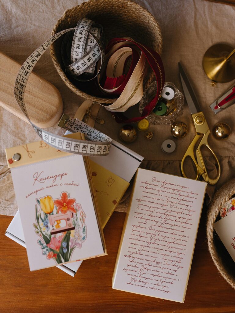 Flat lay of sewing materials and greeting cards on a wooden table.